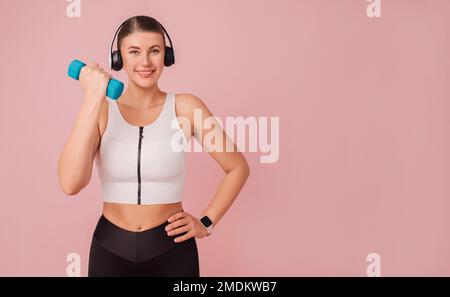 Giovane donna allegra in cuffie che indossano abbigliamento sportivo che fa esercizio sportivo. Fitness conceptAtractive Happy Lady in cuffie con abbigliamento sportivo Foto Stock