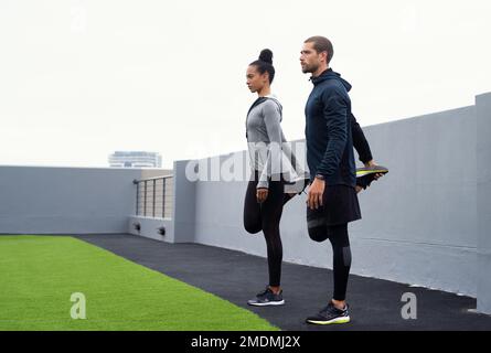 Mantenere la forma della punta superiore. un giovane e una donna sportivi che si allungano mentre si allenano insieme all'aperto. Foto Stock