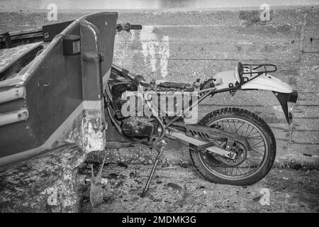 Vecchia motocicletta stazionaria appoggiata al muro in bianco e nero . Foto stock Foto Stock