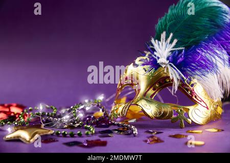 Festa di Carnevale - Una maschera veneziana con perle e paillettes verdi e viola. Sfondo viola con spazio di copia. Il concetto di mascheramento Masquerade. Foto Stock
