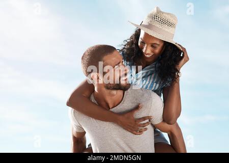 Il nostro amore è qualcosa di speciale. un giovane piggybacking della sua ragazza alla spiaggia. Foto Stock