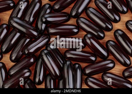 Primo piano scuro di capsule di Omega 3 su sfondo di legno. Vista dall'alto alta risoluzione del prodotto. Concetto di assistenza sanitaria. Foto Stock