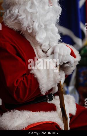 Profondità di campo bassa (fuoco selettivo) dettagli con il costume di Babbo Natale di un uomo durante una festa di Natale dei bambini. Foto Stock