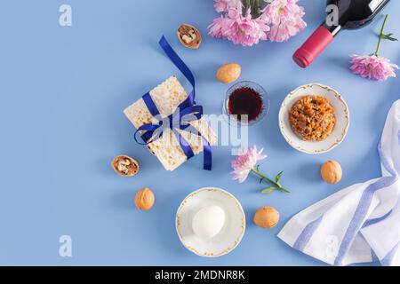 Bella passover sfondo blu della Pasqua ebraica. vista dall'alto di una bottiglia di vino rosso kosher, bicchieri di vino, matzah, noci, uovo su un piatto Foto Stock