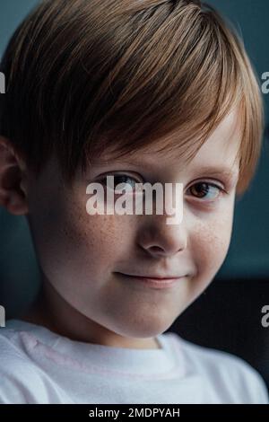 Ritratto rosso testa freckled ragazzo, primo piano. Bambino sorridente. Emozioni facciali espressive. Messa a fuoco selettiva . Foto di alta qualità Foto Stock