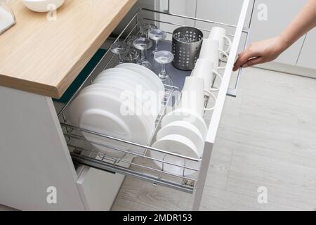 Ripiano estraibile con piatti in una cucina modulare. Mobili da cucina moderni. Produzione di cucine sotto l'ordine, lavori di casa Foto Stock