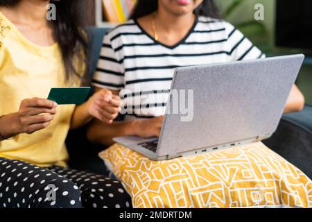 Primo piano shot di mani ragazze occupato fare shopping online o pagamento utilizzando la carta di credito sul computer portatile - concetto di e-commerce, transazioni sicure e. Foto Stock