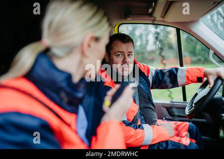 Team di soccorritori che si preparano in auto ambulanza per il funzionamento all'aperto. Foto Stock