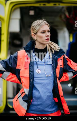 Ritratto di giovane donna medico in piedi di fronte alla macchina ambulanza. Foto Stock