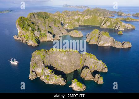 Le isole rocciose, composte di calcare, sorgono dal mare tropicale in Raja Ampat, Indonesia. Queste isole sono antiche barriere coralline innalzate. Foto Stock