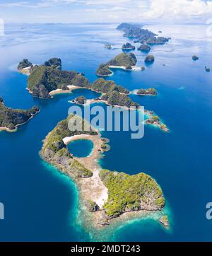 Le isole rocciose, composte di calcare, sorgono dal mare tropicale in Raja Ampat, Indonesia. Queste isole sono antiche barriere coralline innalzate. Foto Stock