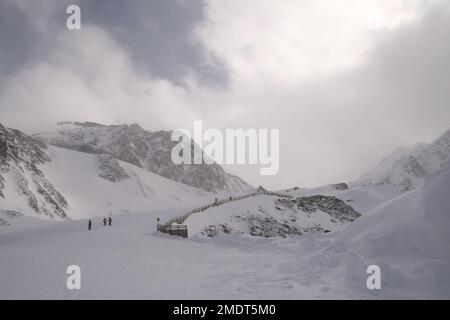 Snowboard e sci sulle Alpi, Austria. Giorno freddo e ventoso, molta neve e montagne nebbiose. Luogo turistico coperto di neve e ghiaccio Foto Stock