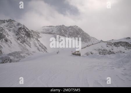 Snowboard e sci sulle Alpi, Austria. Giorno freddo e ventoso, molta neve e montagne nebbiose. Luogo turistico coperto di neve e ghiaccio Foto Stock