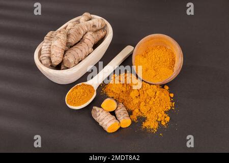 Curcuma - radice di curcuma longa e polvere di curcuma; Foto su sfondo scuro. Foto Stock