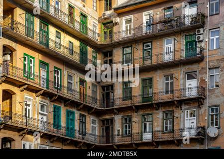 Vecchio edificio tradizionale giallo residenziale a Budapest con gang e porte verdi. Foto Stock