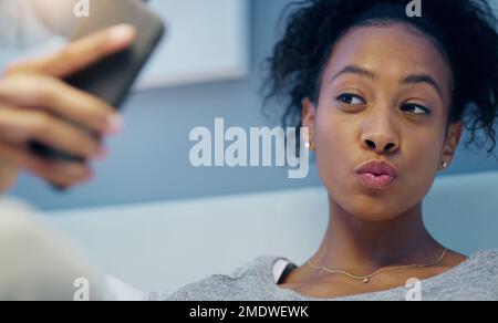 Scattando alcuni scatti prima che ottenga il suo sonno di bellezza. una giovane donna attraente che prende selfie con il suo cellulare mentre si rilassa sul suo letto di notte. Foto Stock