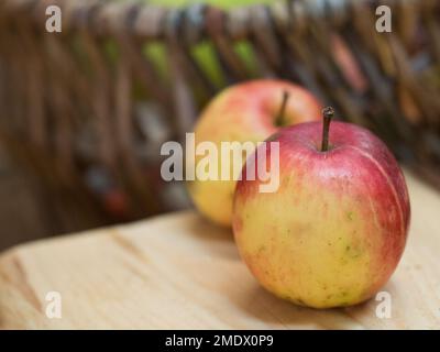 Un primo piano di due mele rosse e giallastre poste su un tavolo di legno Foto Stock