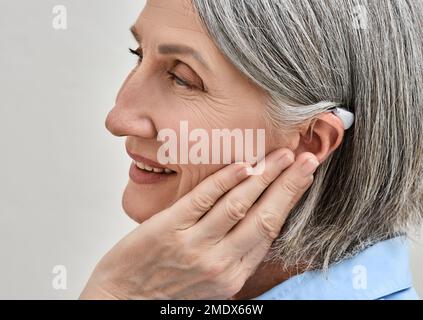 Donna anziana che gode del suono utilizzando gli apparecchi acustici. Riduzione dell'impatto che la perdita uditiva ha sulla vita con gli apparecchi acustici Foto Stock