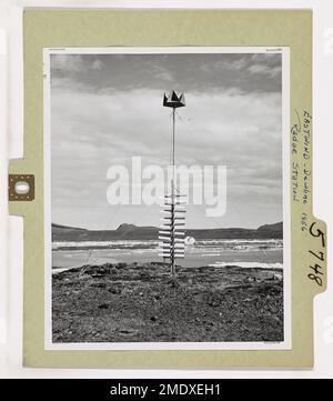 Eastwind - Stazione radar linea Dew 1956. Qui è mostrata una delle nuove torri radar costruite durante l'estate del 1956 ad una stazione radar DELLA LINEA DI RUGIADA (allerta precoce in lontananza) nell'Artico Orientale. Le tavole incrociate dipinte di bianco aiutano a distinguere la torre dal terreno della spiaggia. La guardia costiera statunitense Eastwind, rompighiaccio, consegnava merci e personale per lavorare sulla LINEA DI RUGIADA. A questa stazione diversi Eskimos che vivono nelle vicinanze sono stati impiegati per contribuire a completare la stazione. Foto Stock