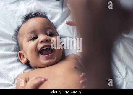Ritratto di un bambino sorridente sdraiato su un letto bianco. Foto di alta qualità Foto Stock