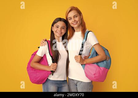 Torna a scuola. Madre e figlia ragazza teen in con zaino. Studenti adolescenti su sfondo giallo isolato. Mamma e bambino vanno a scuola. Foto Stock