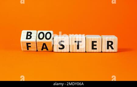 Simbolo Booster e Faster. Parola di concetto Booster più veloce su cubi di legno. Bella tavola arancione sfondo arancione. Business booster e concetto più veloce. Foto Stock