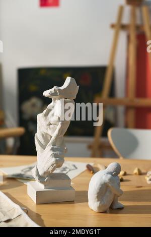 Due piccole figurine in argilla o gesso fatte a mano su un tavolo di legno in studio artigianale o laboratorio che è posto di lavoro di artigiani creativi Foto Stock
