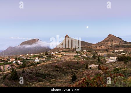 Vista sul villaggio di Ifonche alle località costiere di Los Cristianos e Las Americas all'alba con la luna piena impostazione a ovest, Adeje, Tene Foto Stock