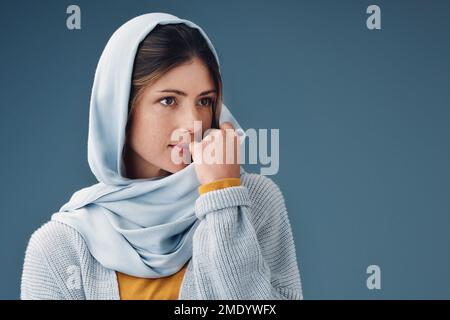 Senso di penitenza. una giovane donna attraente che guarda premurosa mentre si posa su uno sfondo grigio. Foto Stock