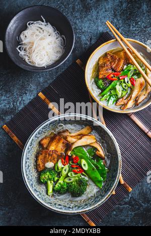 Zuppa di ramen con funghi, verdure, tagliatelle di vetro e maiale Foto Stock