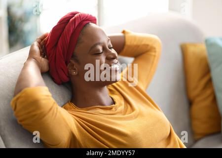 Primo piano di felice donna afroamericana che si aggredisia a casa Foto Stock