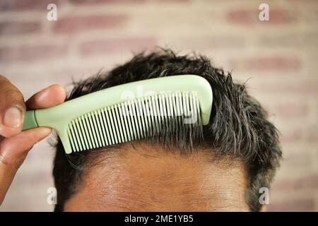 uomo che piega i capelli con il pettine per primo piano Foto Stock