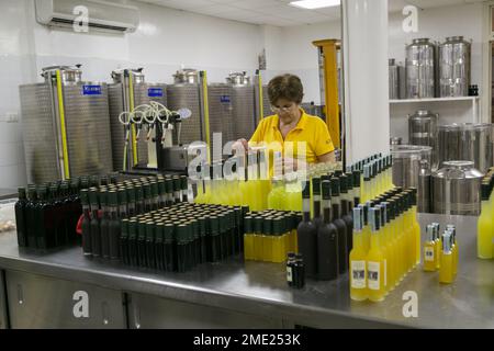 Donna all'interno della fabbrica i Giardini di Cataldo, imbottigliando limoncello e altri liquori a Sorrento, Campania, Italia. Foto Stock