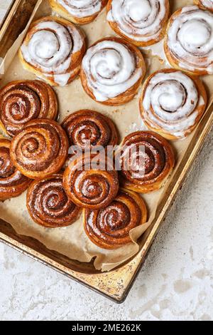 Dolci alla cannella fatti in casa appena sfornati o ciambelle alla cannella su carta da forno Foto Stock