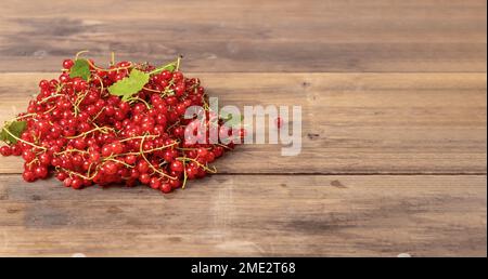 Le bacche di ribes rosso mature giacciono su uno sfondo di legno. Vitamine naturali. Spazio di copia. Messa a fuoco selettiva. Foto Stock