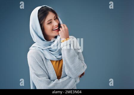 Ceneri nel suo luogo felice. una giovane donna attraente che guarda premurosa mentre si posa su uno sfondo grigio. Foto Stock