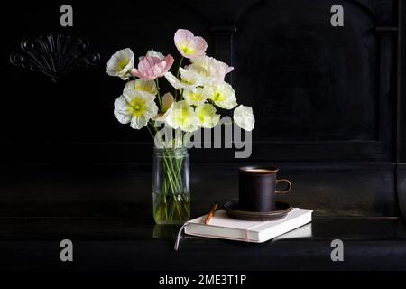 Islanda fiori di papavero in vaso di vetro da caffè e diario su pianoforte nero Foto Stock