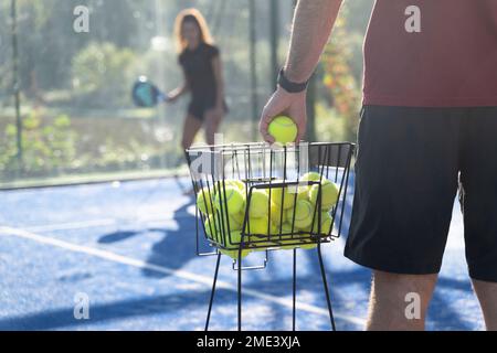 Uomo con palla da tennis e donna in piedi sullo sfondo Foto Stock