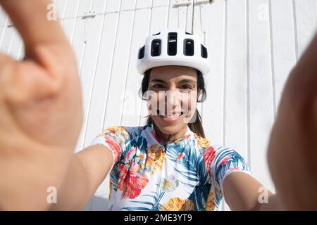 Ciclista felice prendendo selfie davanti al muro Foto Stock