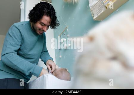 Felice padre che cambia i vestiti del bambino nel paese Foto Stock