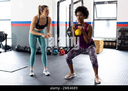 Diverse donne in forma che si allenano e usano il kettlebell in palestra Foto Stock