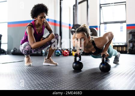 Diverse donne in forma che si allenano e utilizzano le campane di un kettlebells in palestra Foto Stock