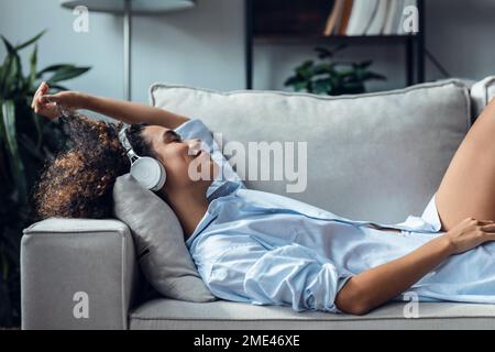 Giovane donna rilassante sul divano di casa Foto Stock