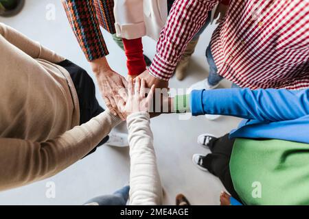 Uomini d'affari e donne d'affari diversi impilando le mani in ufficio Foto Stock