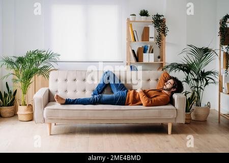 Giovane uomo rilassante sul divano di casa Foto Stock