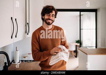 Felice giovane uomo che asciuga le mani con tovagliolo a casa Foto Stock