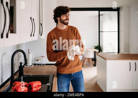 Uomo felice che asciuga le mani con tovagliolo a casa Foto Stock