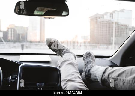 Uomo con i piedi sul cruscotto in auto Foto Stock