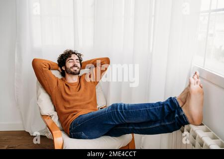 Felice giovane uomo con gli occhi chiusi rilassandosi in poltrona Foto Stock