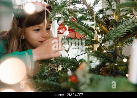 Ragazza decorare albero di Natale a casa Foto Stock